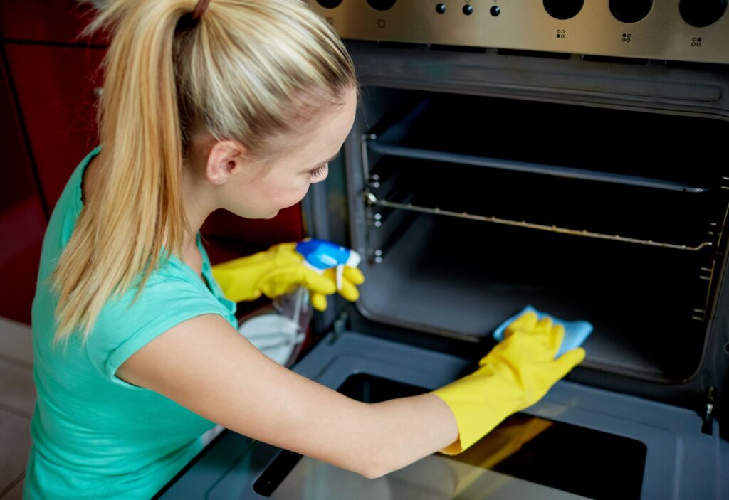 pessoas-trabalho-domestico-e-conceito-de-limpeza-mulher-feliz-com-garrafa-de-limpador-de-spray-limpando-forno-na-cozinha-de-casa (1)